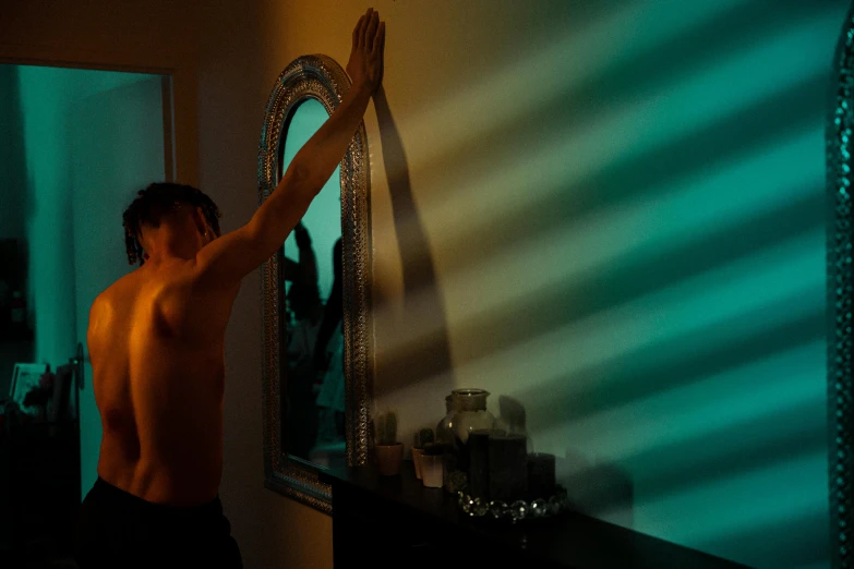 a person is standing in front of a mirror holding his arms up