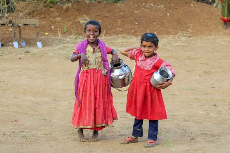 two children with metal pots standing next to each other