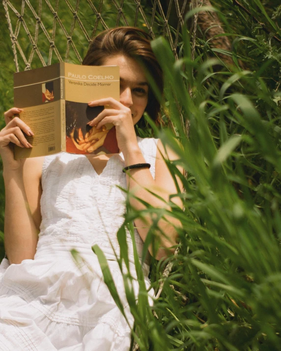 a woman laying in the grass while reading a book