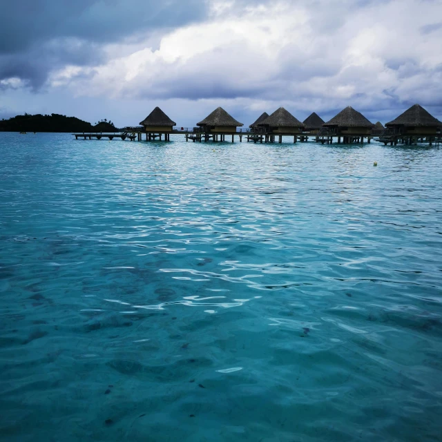 a group of huts on water on the ocean