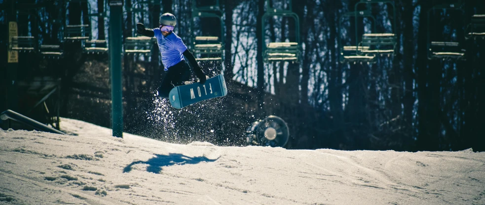 a person is snowboarding down a hill with trees