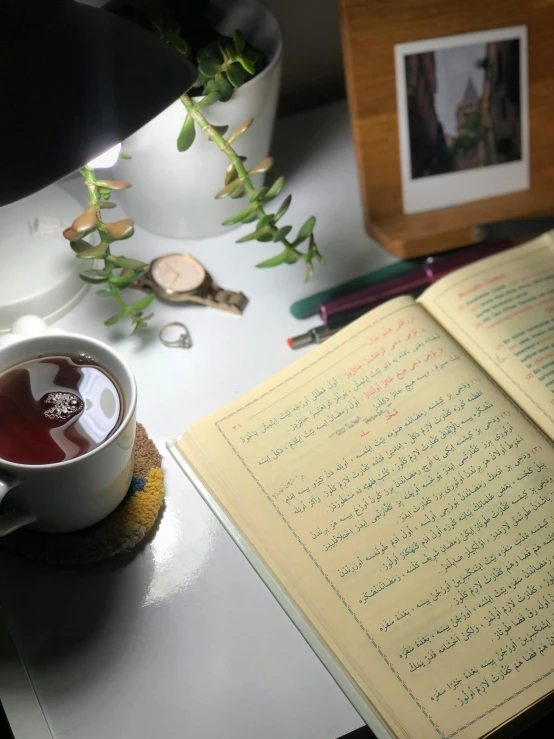 a note pad, cup of tea and vase with flowers