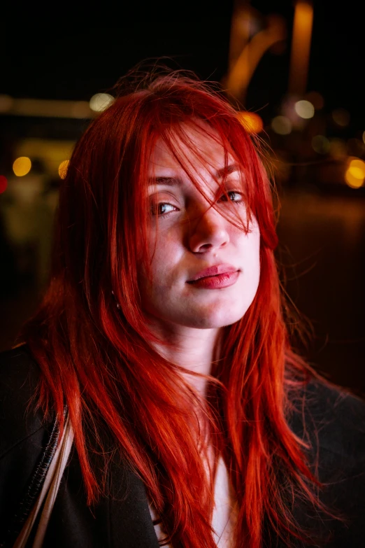 red headed woman with long hair on a street corner at night