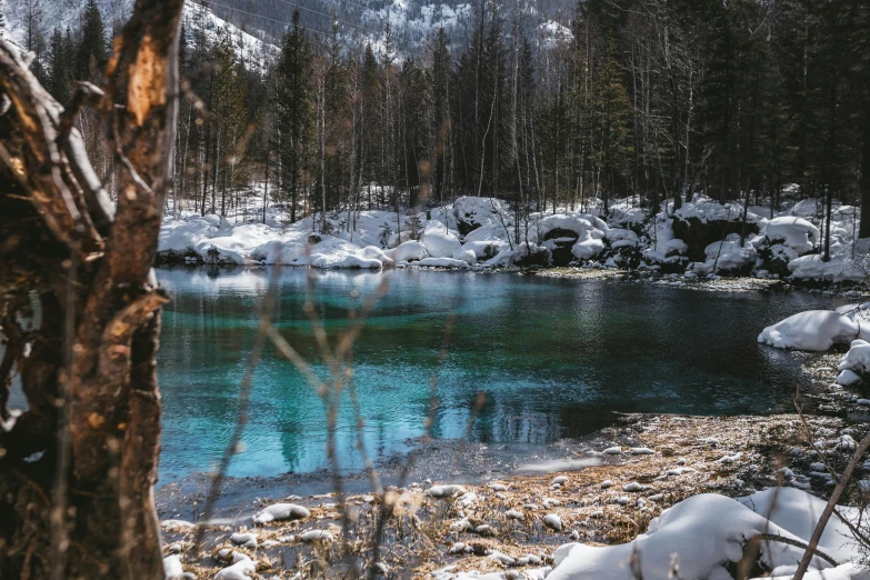 a blue river with clear water surrounded by snow