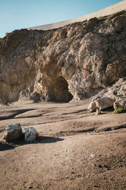 a lone giraffe walking away from a rock formation