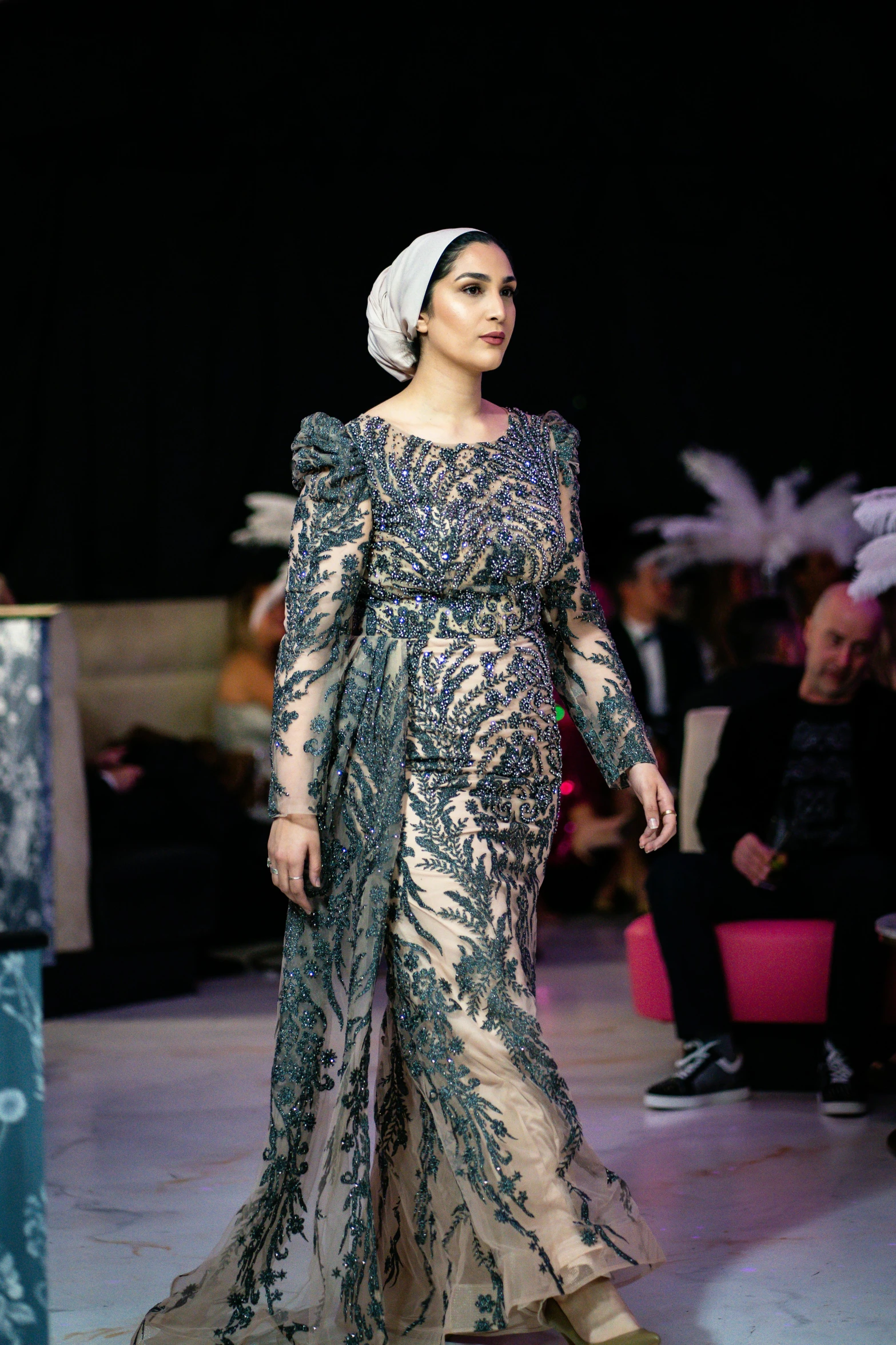 a woman wearing a head wrap and long dress on the runway