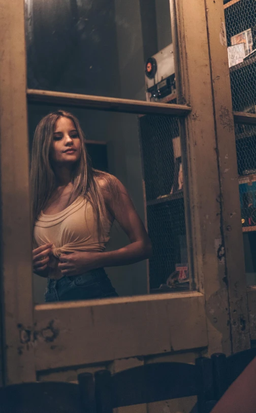 a girl standing by the window looking through