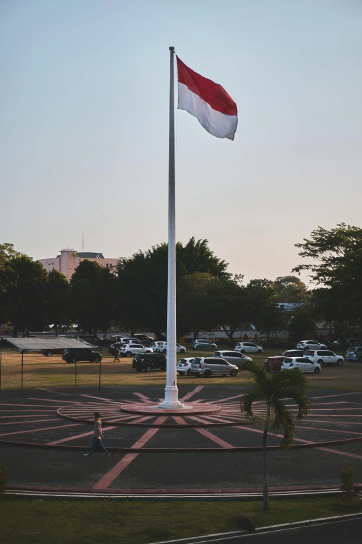 the flag of thailand is on a pole in a parking lot