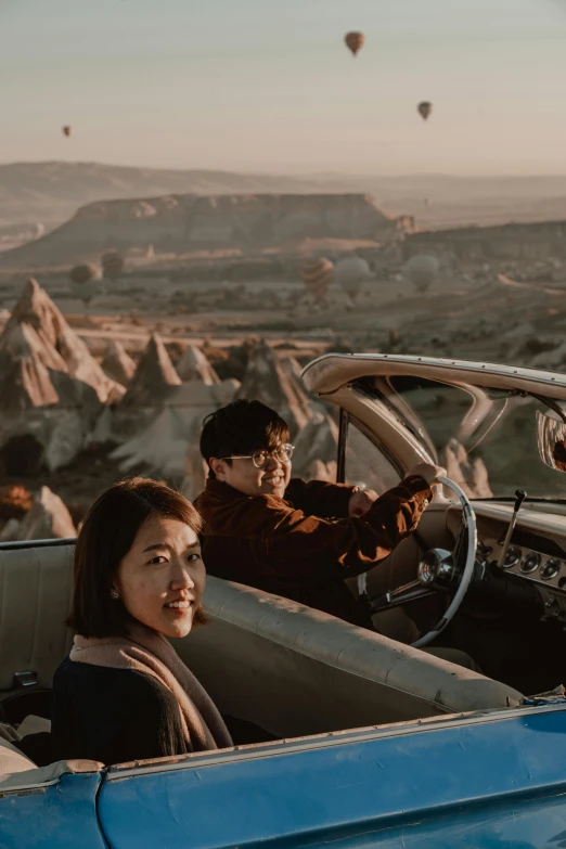 a young woman sits in the drivers seat of a car in front of a man and child