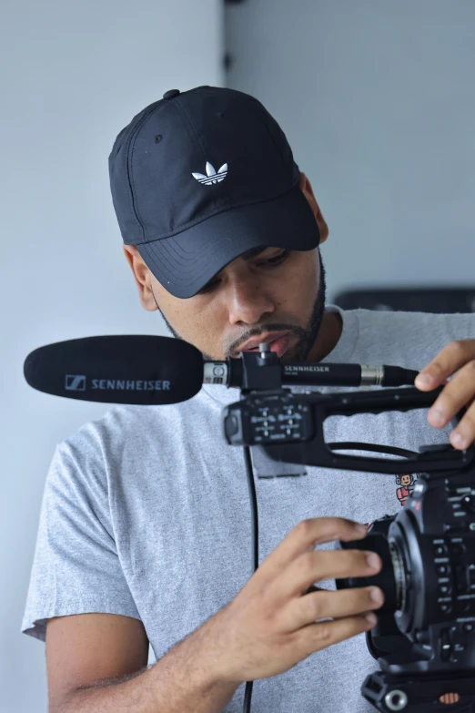 a man wearing a cap is holding a camera and a microphone