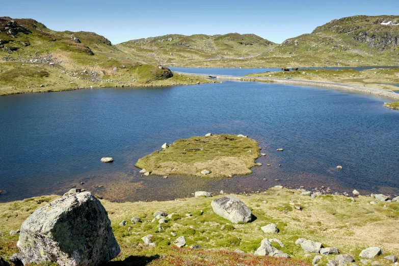 a pond surrounded by rocks and grass