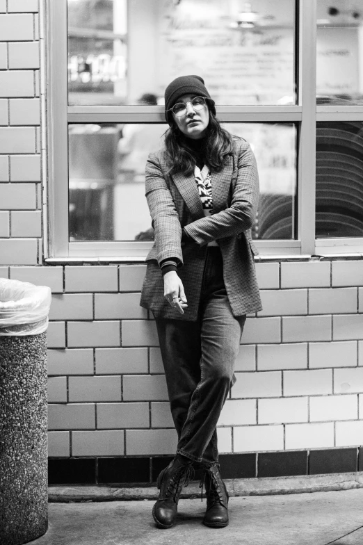 the woman stands in front of a building near a window