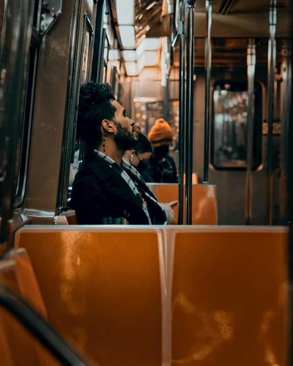 a man in a black jacket is sitting on a train