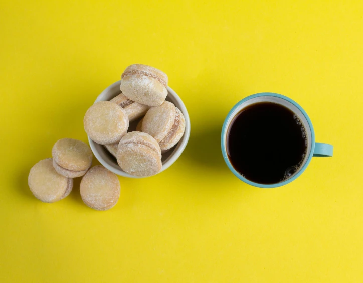 a cup of coffee and several donuts sitting on a yellow surface