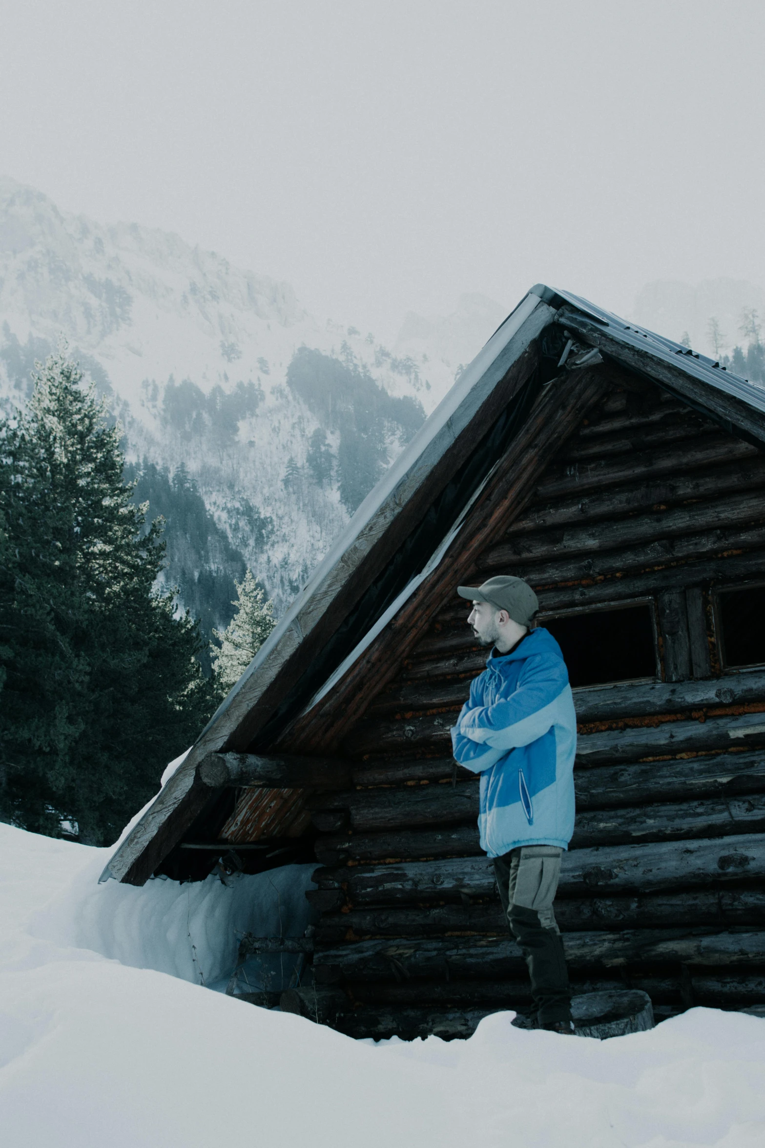 a woman standing next to a log cabin in snow