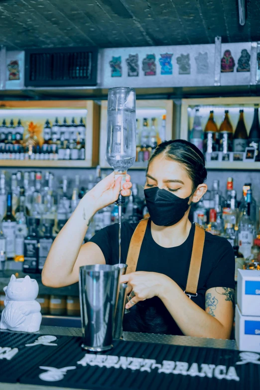 a person wearing a face mask behind a bar