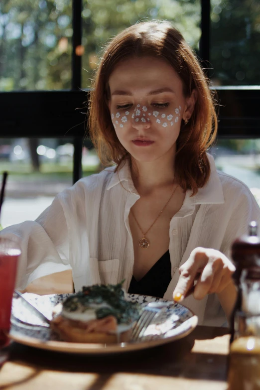 woman with fake eye contact on her eyes sits at table with food