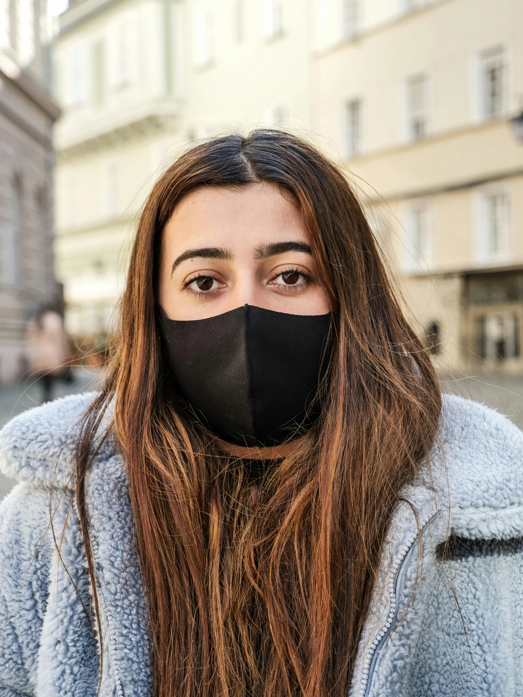 a woman with long hair wearing a black face mask