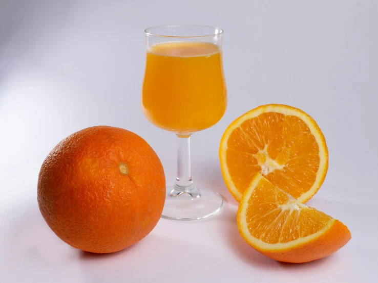 an orange next to a glass of juice