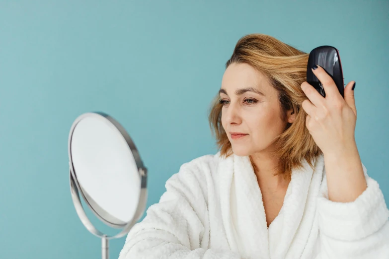 woman in robe holding up hairdryer to her face