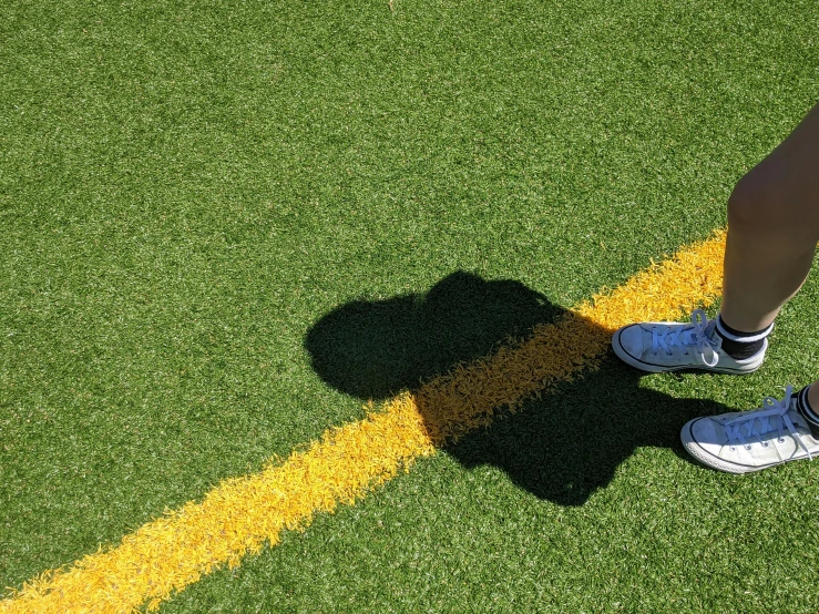 a shadow of someone standing in the grass