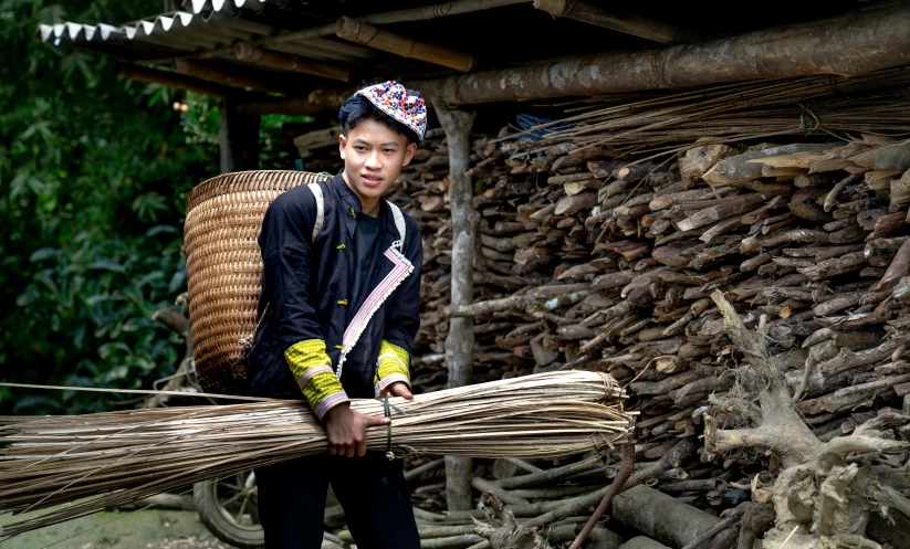 a  poses for the camera holding a large bundle of wood