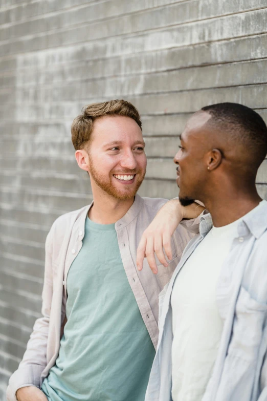 two men standing close to each other near a building