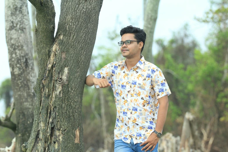 a man wearing glasses holding onto a tree