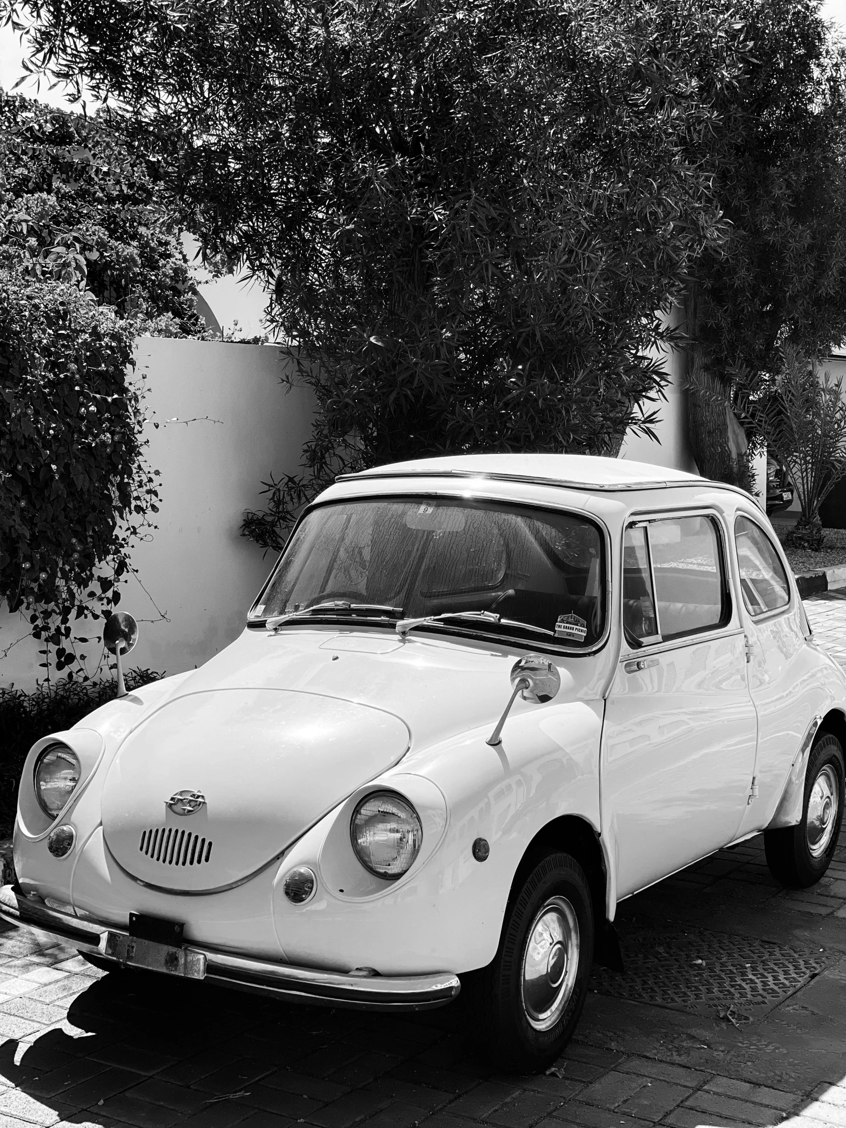 the white car has an old fashioned surfboard on top of it