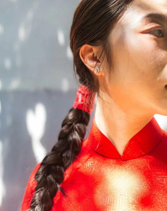 young woman with ponytail standing in front of white wall