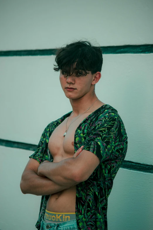 a man poses with his shirt on and his arms folded