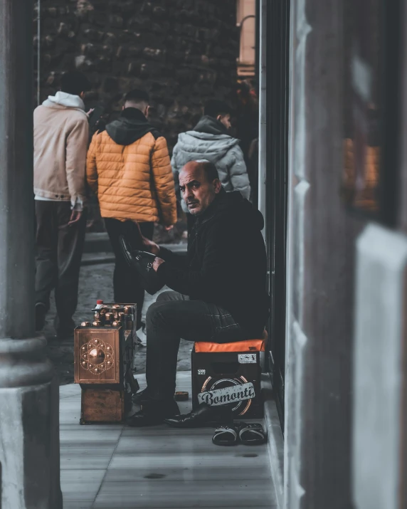 a man sitting on the sidewalk in front of a building