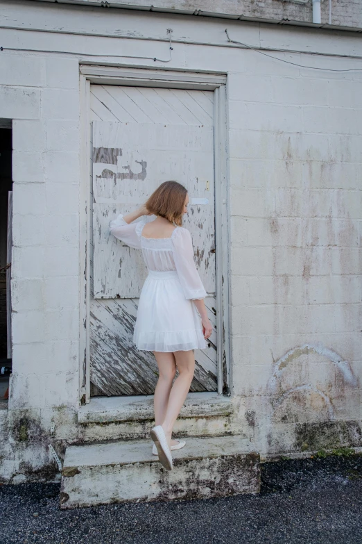 a woman standing in the doorway of a building wearing a short dress and white socks