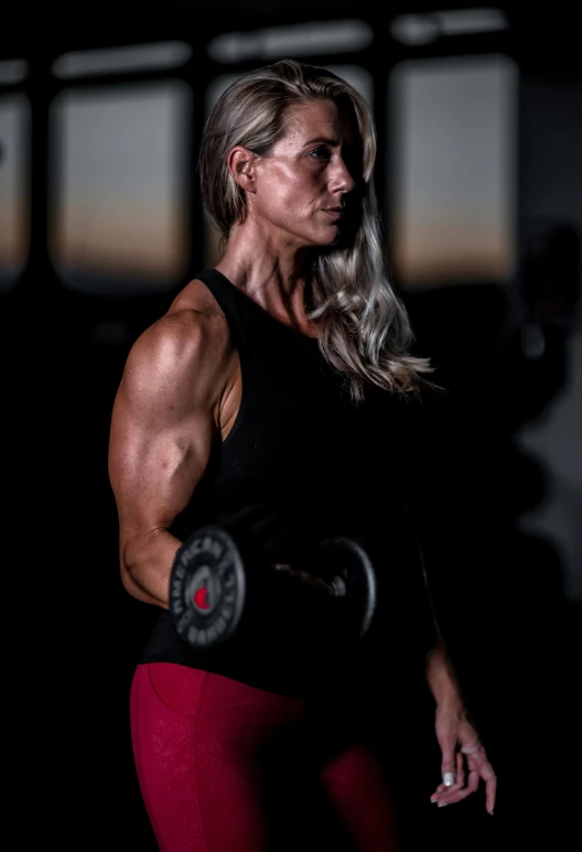 woman with big muscles holding dumbs with barbells in both hands