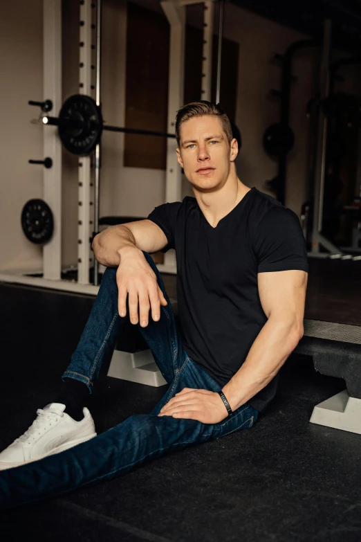 a man in jeans and a t - shirt sits on the ground