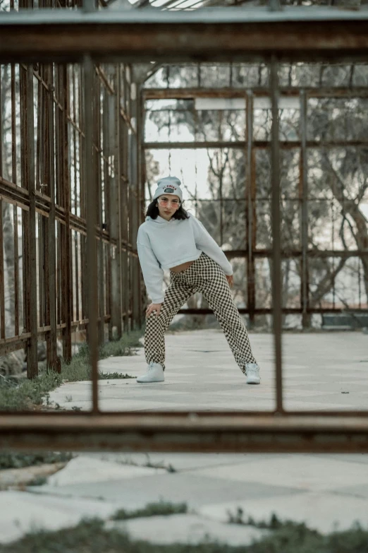 woman in plaid pants posing near rusty fence