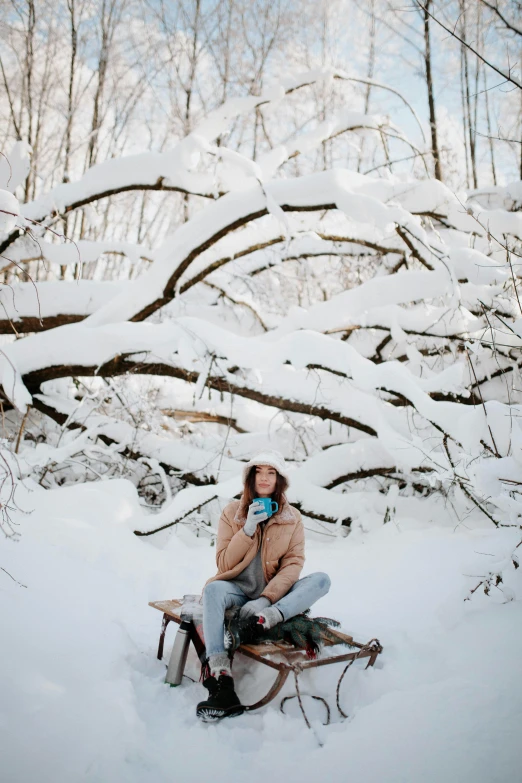 a woman in her thirties sitting on a sled and talking on a cell phone