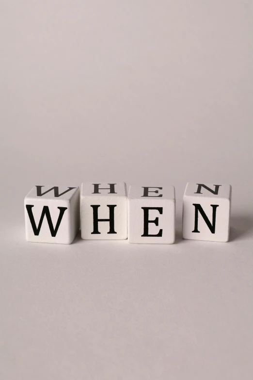 a white cube that reads when and is spelled with black letters