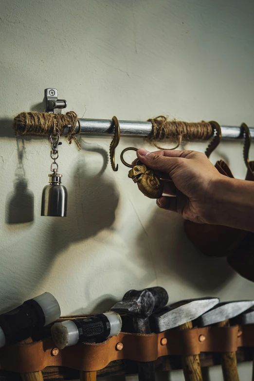 someone is holding a pair of long knives and keys on a wall