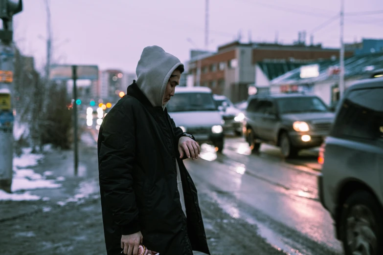 an older man is waiting in the rain to cross the street