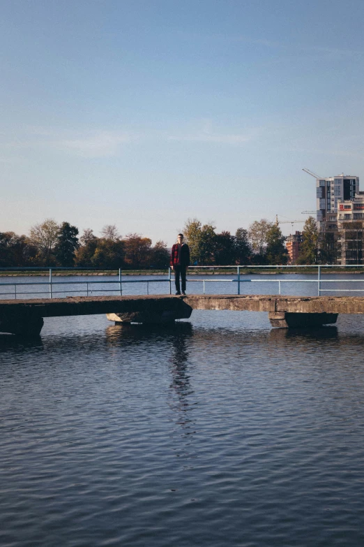 man walking across a bridge over water near a river