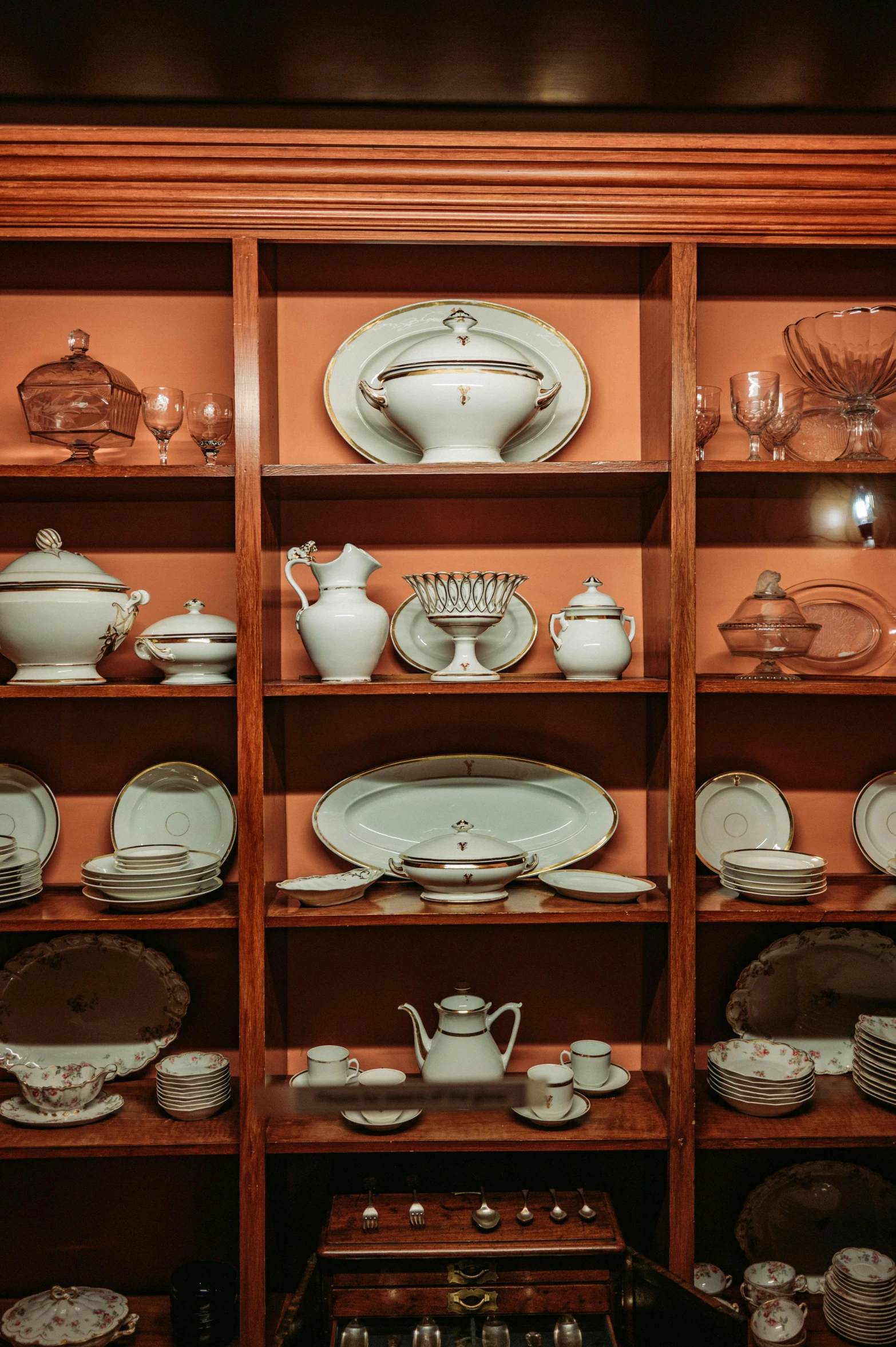 a glass case full of china with plates and dishes on top