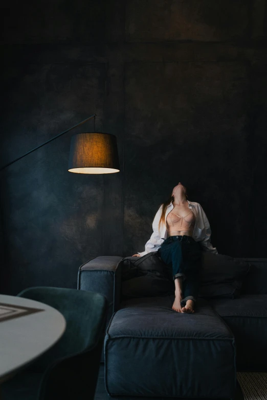 a girl is sitting on a couch in a dark room