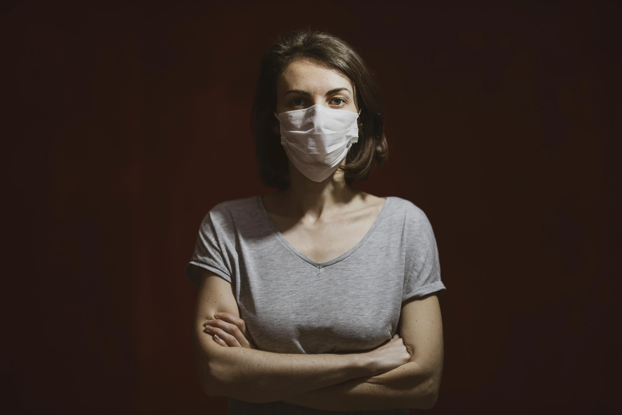 a woman in a mask stands with her arms crossed