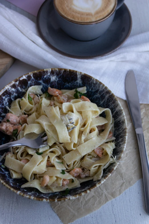 bowl full of pasta next to a cup with a spoon