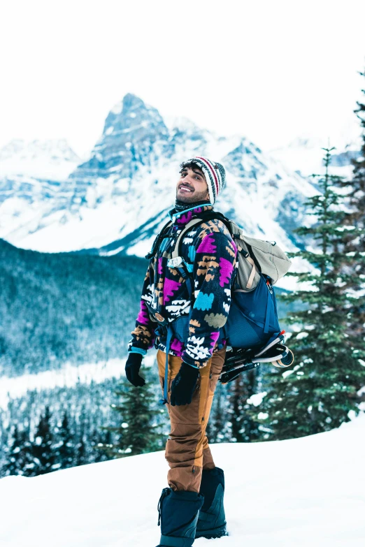 man standing on snowy surface with mountains and sky in background