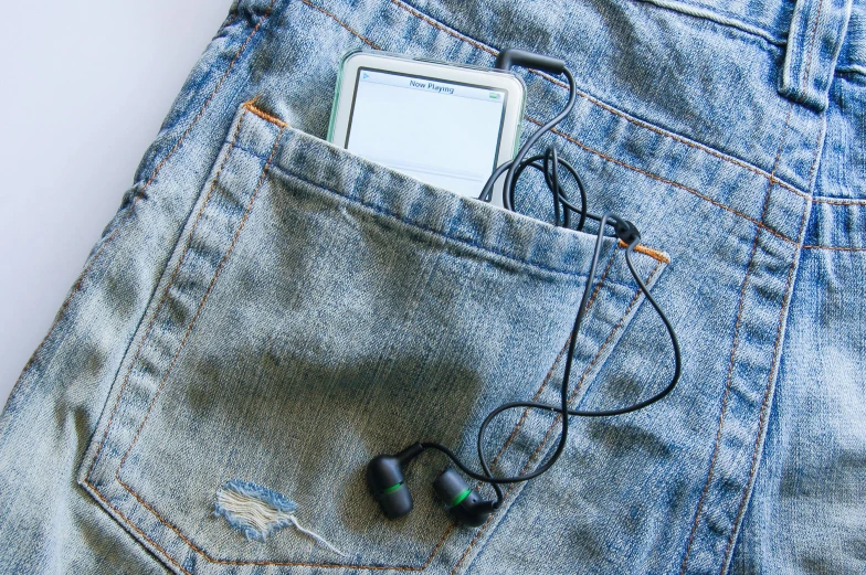 a cell phone and some earphones laying in the pocket of a jeans pocket