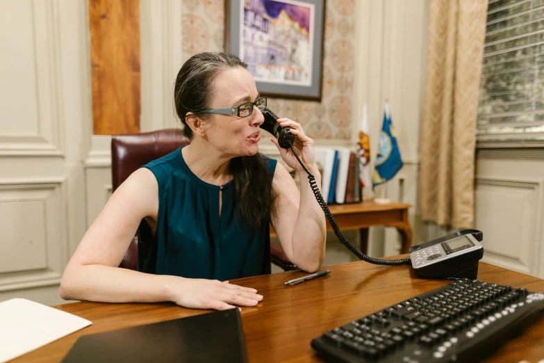 a woman sitting at a desk while talking on the phone