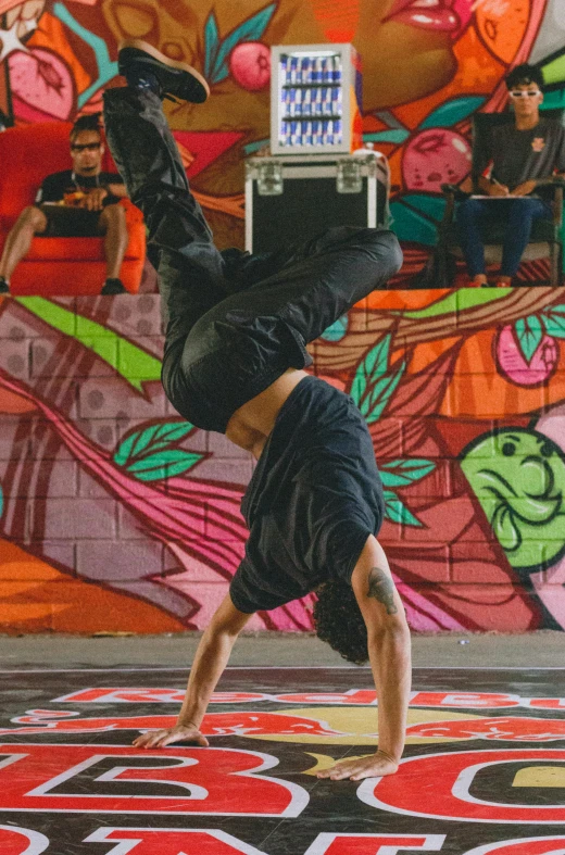 a young man does a handstand with a speaker on his head