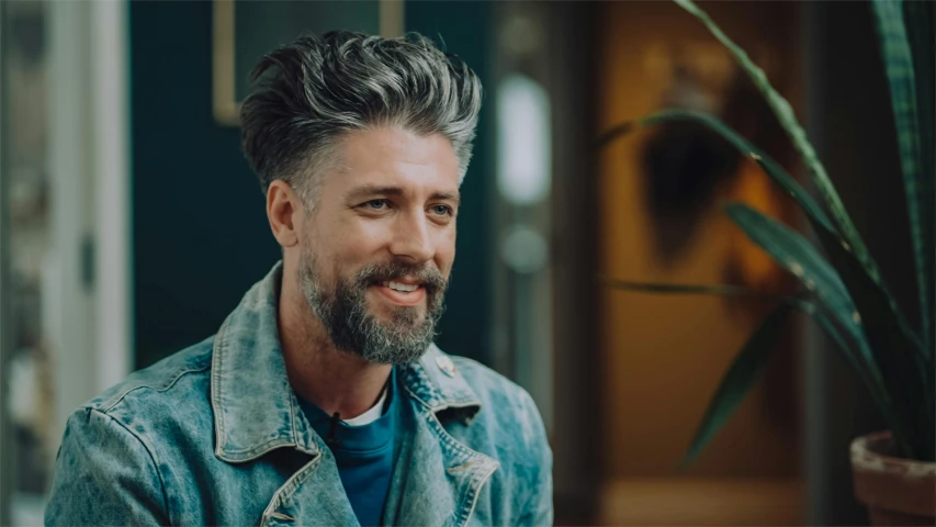 man with beard looking off to side wearing blue jeans